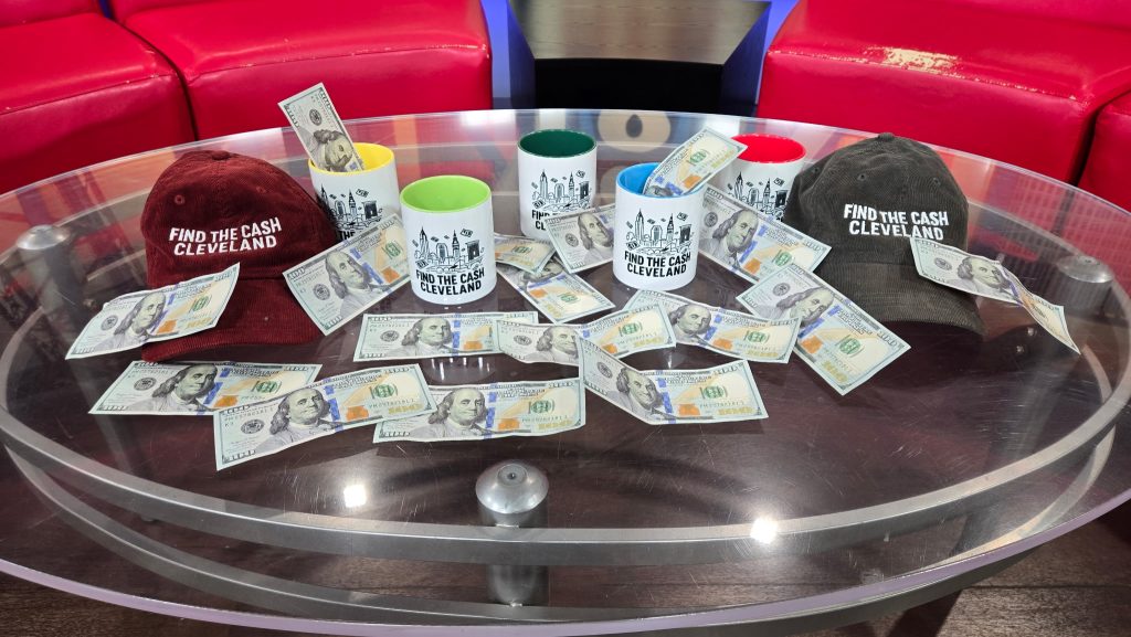 Stacks of dollar bills displayed on the FOX 8 News morning show table as a prop during an early segment featuring Find the Cash Cleveland’s creator, Khristian Santana, discussing Cleveland’s viral real-life treasure hunts.