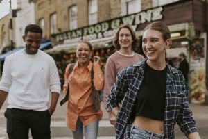 Cheerful diverse group of friends walking through Cleveland streets, smiling and searching for hidden cash during a Find The Cash Cleveland event.
